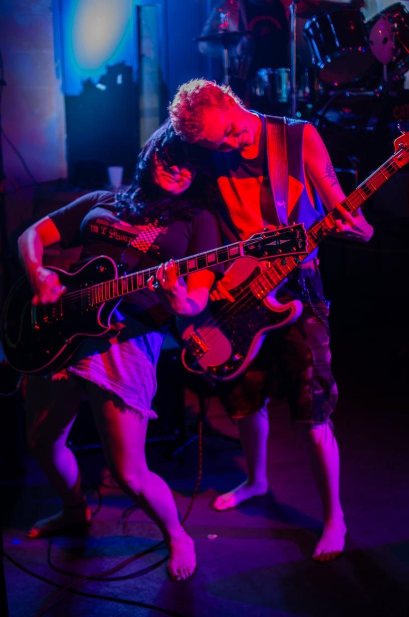 Catch These Hands guitarists playing under purple light